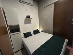 a small bedroom with a bed with two green pillows at Suíte Neblina in Garanhuns