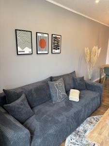 a gray couch in a living room with pictures on the wall at 100qm Apartment mit Regendusche & Top-Lage in Mücheln