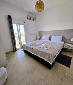 a bedroom with a large bed and a large window at ClaudiAgapi Apartments Korfu in Agios Stefanos