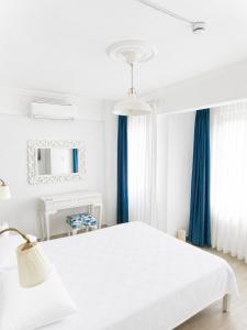 a white bedroom with blue curtains and a bed at Hayal Ada in Bozcaada