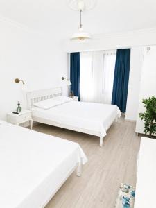 two beds in a white room with blue curtains at Hayal Ada in Bozcaada +7 photos