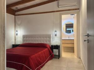 a bedroom with a red bed and a mirror at Villa Oronzo in Torre Lapillo