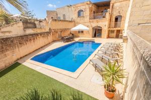 a swimming pool with chairs and a house at Centre Island Gozitan Farmhouse & Pool - Happy Rentals in Kerċem