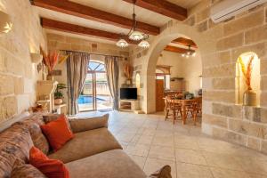 a living room with a couch and a stone wall at Centre Island Gozitan Farmhouse & Pool - Happy Rentals in Kerċem