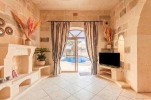 a living room with a tv and a large window at Centre Island Gozitan Farmhouse & Pool - Happy Rentals in Kerċem