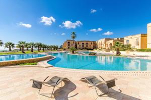 a swimming pool with two chairs and buildings at Harbour Views Gozitan Villa Shared Pool - Happy Rentals in Mġarr +21 photos