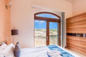a bedroom with a bed and a large window at Harbour Views Gozitan Villa Shared Pool - Happy Rentals in Mġarr