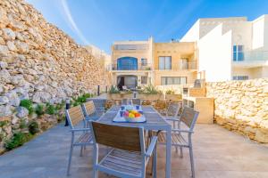 a patio with a table and chairs and a building at Ta'Siku Gozitan villa Pool & hot tub - Happy Rentals in Il-Pergla