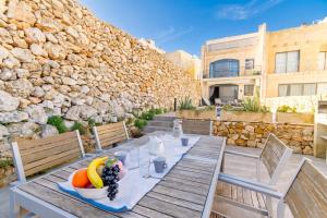 a wooden table with a bowl of fruit on it at Ta'Siku Gozitan villa Pool & hot tub - Happy Rentals in Il-Pergla