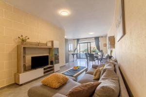 a living room with a couch and a television at Ta'Siku Gozitan villa Pool & hot tub - Happy Rentals in Il-Pergla +26 photos