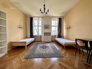 a bedroom with two beds and a table and a rug at Pokoje Zwycięstwa in Gliwice