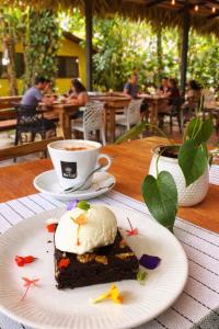 a piece of cake on a plate with a cup of coffee at Casa Merlin Yoga & Welness Hotel in Puerto Viejo
