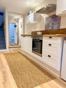 a kitchen with white cabinets and a rug at L'Échappée iodée à "La Cahute" - Rénovée, Calme & Proche Mer in Ambleteuse