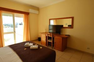 a hotel room with a bed and a desk with a mirror at Rialgarve in Faro
