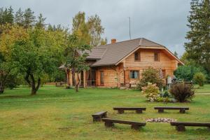 a log cabin with benches in front of it at Purgaiļi in Smiltene