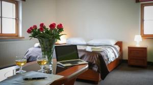 a bedroom with a bed and a table with a laptop and flowers at Apartamenty Maciejowy Sad in Sady Dolne