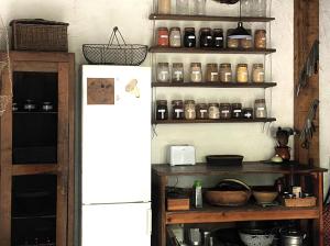 a kitchen with a refrigerator and shelves with jars at La Maison dans la forêt in Vabre