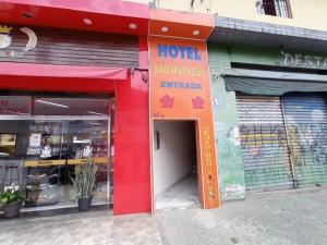 an entrance to a store with a red building with a door at Hotel São Mateus in São Paulo