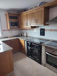 a kitchen with black appliances and wooden cabinets at Apartamento Duplex con jardín A Casiña de Divina in Lago