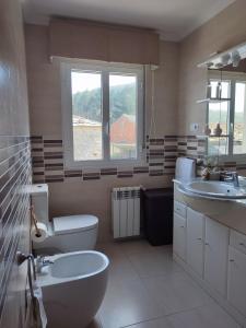 a bathroom with two sinks and a toilet and a window at Apartamento Duplex con jardín A Casiña de Divina in Lago