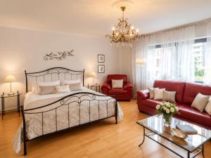 a bedroom with a bed and a red couch at Erholungs-Apartment mit Balkon nahe Therme & Klinik in Bad Lippspringe