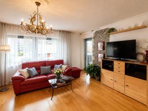 a living room with a red couch and a flat screen tv at Erholungs-Apartment mit Balkon nahe Therme & Klinik in Bad Lippspringe