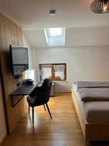 a bedroom with a desk with a bed and a television at Schererhof in Rimsting