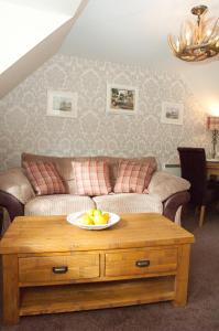 una sala de estar con sofá y un bol de fruta en una mesa en Strathspey Cottage en Carrbridge