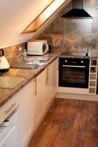 a kitchen with white cabinets and a sink and a microwave at Strathspey Cottage in Carrbridge