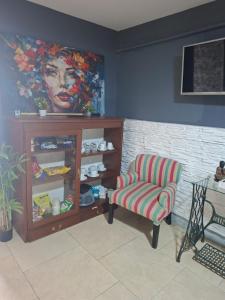 a living room with a chair and a painting at Sol y Luna Hospedaje in Monte Grande