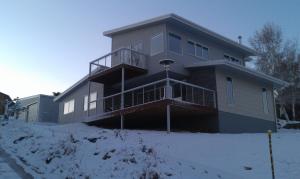 a house with a balcony in the snow at Jindabyne Guest House in Jindabyne