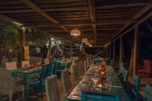 a long table in a restaurant with blue chairs at Blue Mango Beach Hotel in Guachaca