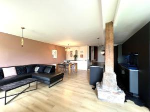 a living room with a black couch and a fireplace at L'Héritage, Loft design et pierre in Dol-de-Bretagne