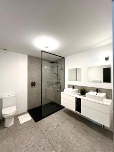 a bathroom with a toilet and two sinks and a shower at L'Héritage, Loft design et pierre in Dol-de-Bretagne +27 photos