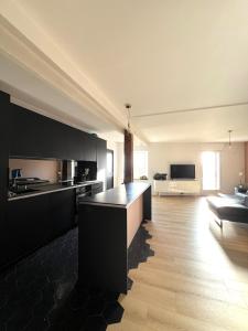 a kitchen with black cabinets and a living room at L'Héritage, Loft design et pierre in Dol-de-Bretagne