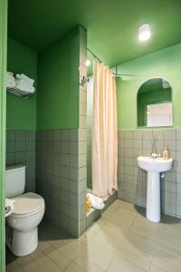 a green bathroom with a toilet and a sink at Winnedumah Hotel in Independence