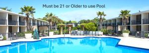 a swimming pool in front of a building with palm trees at Royal Holiday Beach Resort in Biloxi