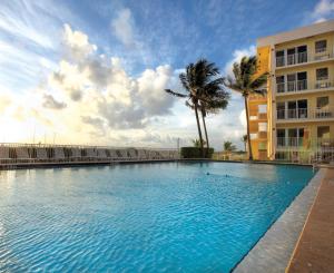 a large swimming pool next to a building and palm trees at Sea Gardens Resort Studio Suite in Pompano Beach