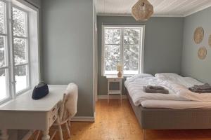 a bedroom with a bed and a desk and two windows at Cozy forest cabin in Vik