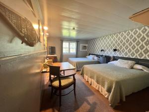 a bedroom with two beds and a table and a desk at Barron Brook Inn in Whitefield