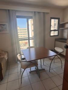 a dining room table and chairs in a room with a window at Flat a Beira Mar in Caraguatatuba