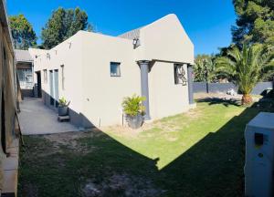 a small white house with a grass yard at Aquasaints Sandton Logde in Johannesburg