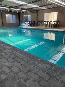a swimming pool with blue water and chairs in it at Aquasaints Sandton Logde in Johannesburg