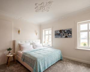 a white bedroom with a bed and two windows at Kapitänsapartment in der VILLA KAETHE am Kurpark - moderne & stilvolle 65qm Ferienwohnung nahe Strand in Warnemünde