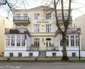 a yellow and white building with a tree at Kapitänsapartment in der VILLA KAETHE am Kurpark - moderne & stilvolle 65qm Ferienwohnung nahe Strand in Warnemünde