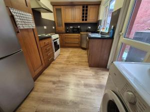 a small kitchen with wooden cabinets and a dishwasher at Hanna house in Belfast