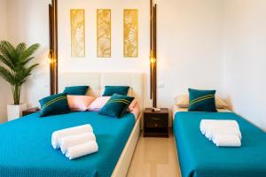 two beds in a room with blue sheets at Monolocale elegante con design moderno e atmosfera tropical chic in Nardò