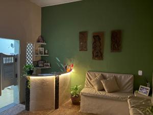 a living room with a couch and a green wall at Quarto confortável no Centro- Wi-Fi rápido, ar-condicionado in São Luís