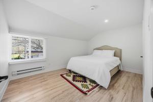 a white bedroom with a bed and a window at Lake Drive apartment in Georgina