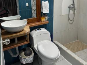 a bathroom with a white toilet and a sink at Casa Descanso y Madera in Baños